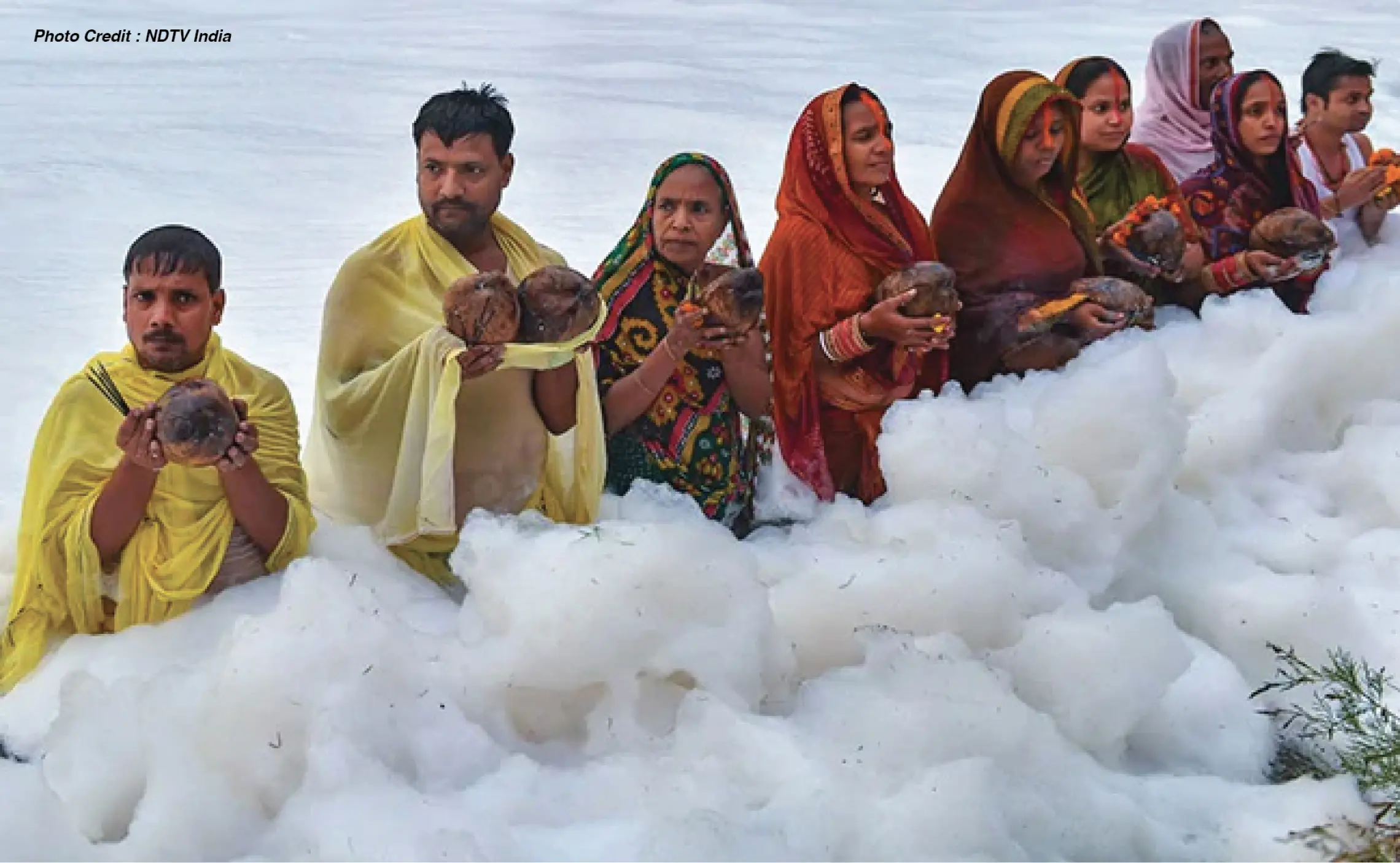 devotee performing rituals in the yamuna river covered in froth